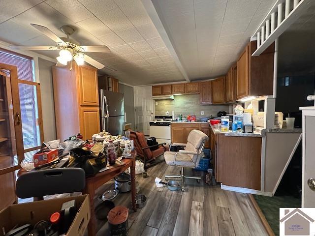 kitchen with stove, hardwood / wood-style floors, stainless steel fridge, and ceiling fan