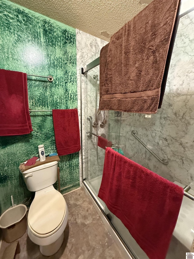 bathroom featuring a shower with shower door, a textured ceiling, and toilet