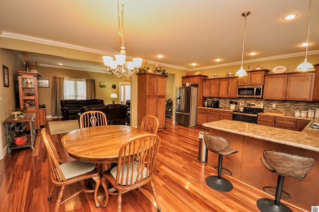 dining area with crown molding, a chandelier, and light wood-type flooring