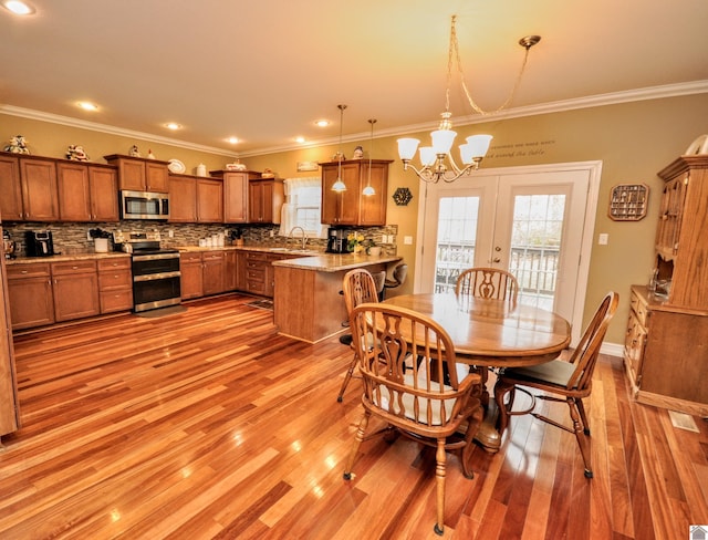 dining room featuring crown molding, sink, a notable chandelier, and light wood-type flooring