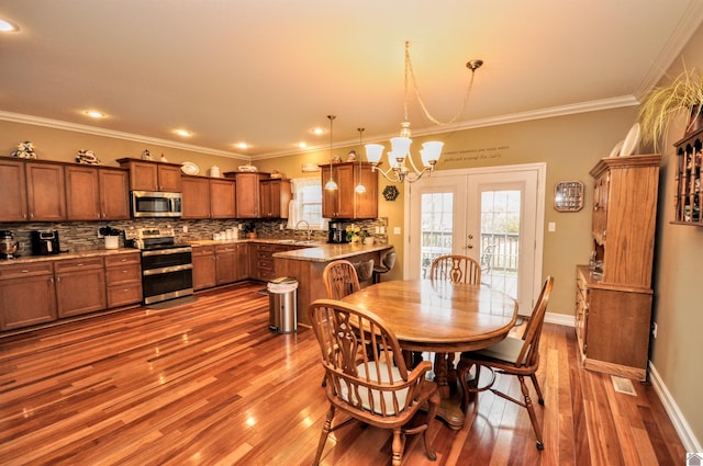 dining room featuring a notable chandelier, ornamental molding, light hardwood / wood-style floors, and french doors