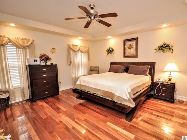 bedroom featuring wood-type flooring, a raised ceiling, and ceiling fan