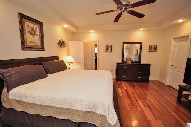 bedroom featuring dark hardwood / wood-style floors, ceiling fan, and a tray ceiling