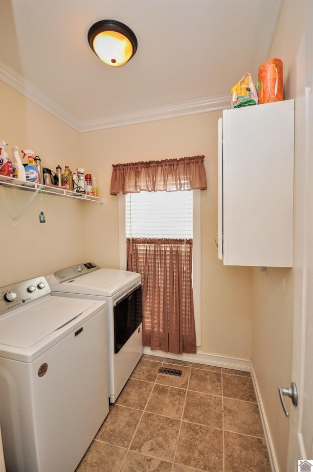 clothes washing area featuring cabinets, crown molding, washer and dryer, and dark tile patterned flooring