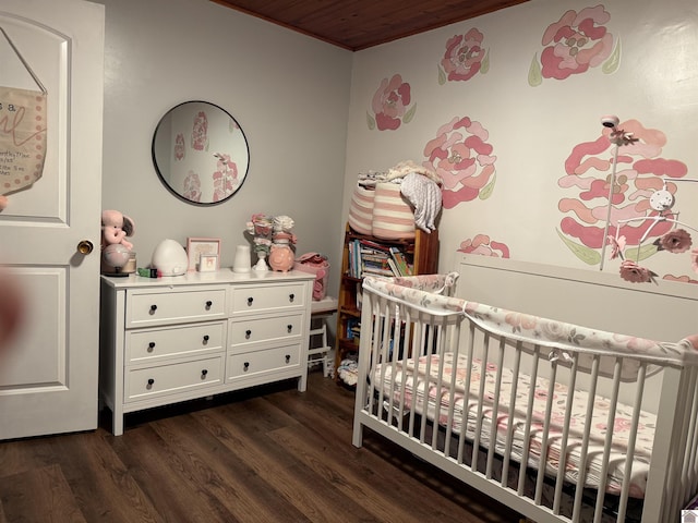 bedroom with a nursery area and dark hardwood / wood-style flooring