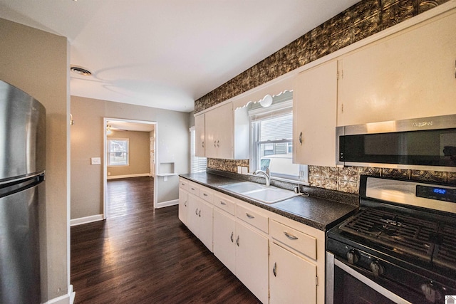 kitchen featuring appliances with stainless steel finishes, dark hardwood / wood-style floors, tasteful backsplash, white cabinetry, and sink