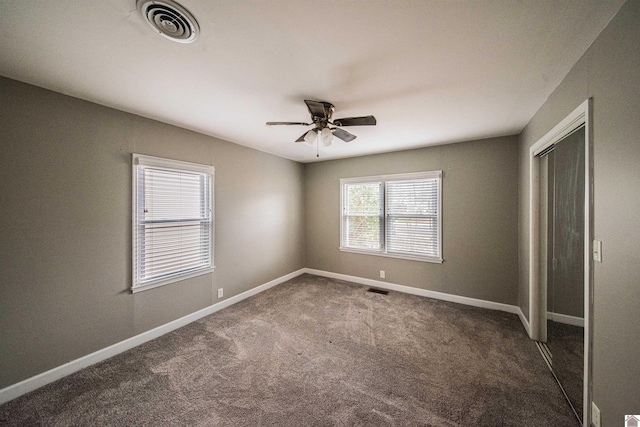 unfurnished bedroom with ceiling fan, a closet, and dark colored carpet