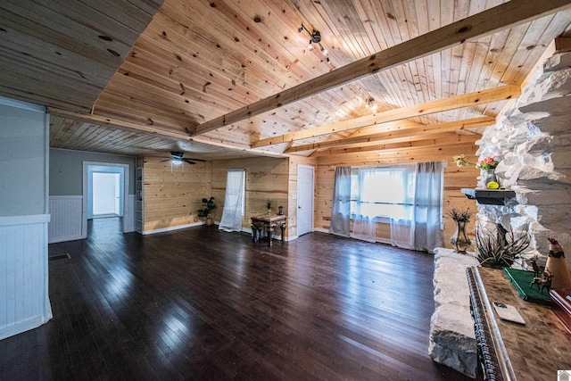 unfurnished living room with ceiling fan, dark wood-type flooring, wooden ceiling, and beamed ceiling