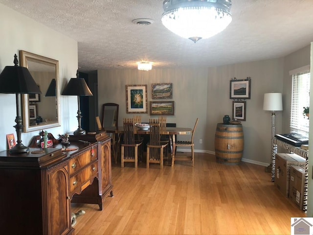 dining space featuring light hardwood / wood-style flooring and a textured ceiling