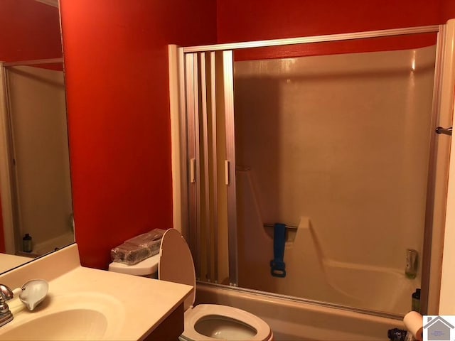 full bathroom featuring vanity, combined bath / shower with glass door, and toilet