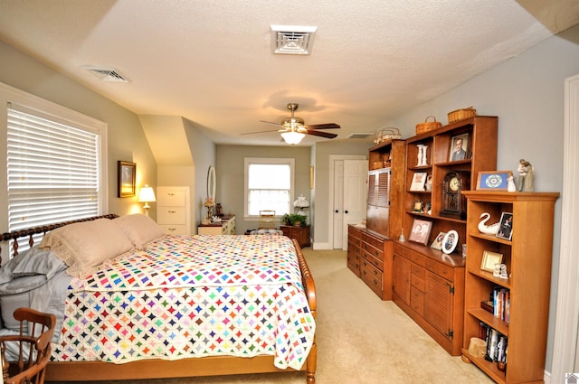 bedroom featuring ceiling fan, light carpet, and a textured ceiling