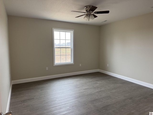 empty room with a textured ceiling, dark wood-type flooring, and ceiling fan