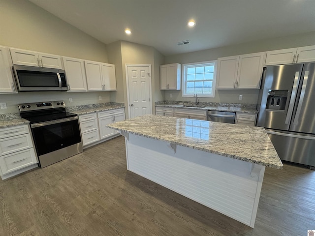 kitchen featuring white cabinetry, light stone counters, a center island, and appliances with stainless steel finishes