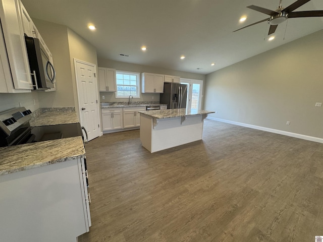 kitchen featuring sink, a kitchen island, stainless steel appliances, light stone countertops, and white cabinets