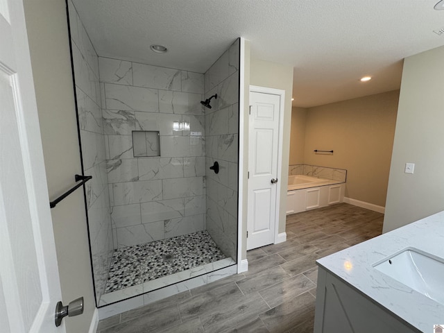 bathroom with vanity, independent shower and bath, and a textured ceiling