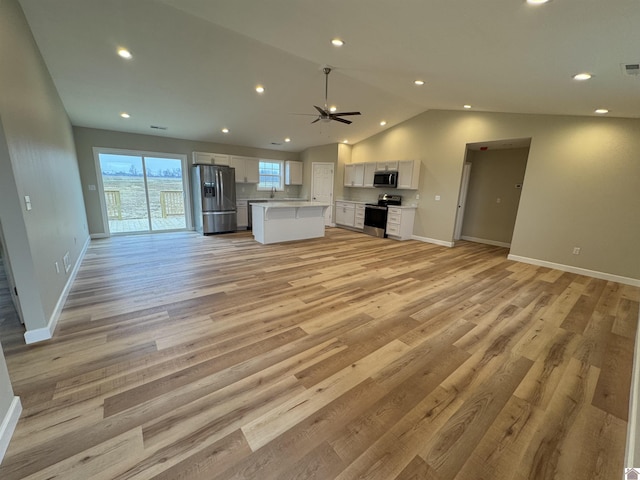 unfurnished living room featuring lofted ceiling, sink, ceiling fan, and light hardwood / wood-style flooring