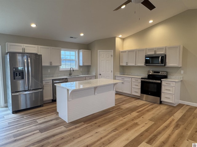 kitchen with white cabinetry, sink, stainless steel appliances, and a kitchen island