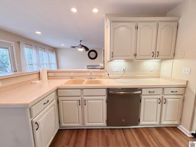 kitchen with sink, hardwood / wood-style floors, tasteful backsplash, white cabinets, and stainless steel dishwasher