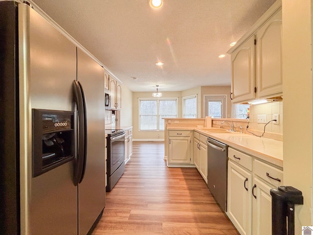 kitchen featuring sink, light hardwood / wood-style flooring, appliances with stainless steel finishes, a textured ceiling, and decorative backsplash