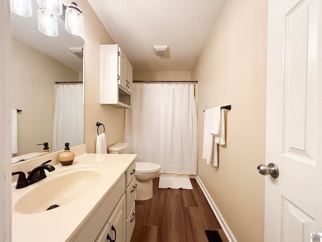 bathroom featuring vanity, toilet, hardwood / wood-style floors, and a textured ceiling