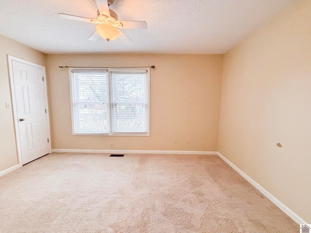 empty room featuring ceiling fan, light colored carpet, and a textured ceiling