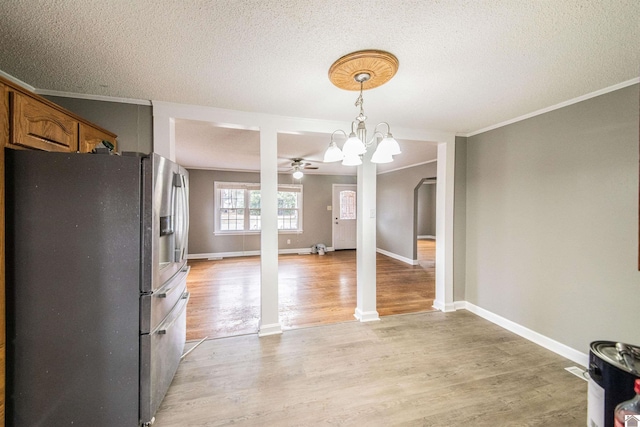 unfurnished dining area featuring crown molding, a chandelier, a textured ceiling, and light hardwood / wood-style flooring