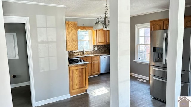 kitchen with pendant lighting, appliances with stainless steel finishes, crown molding, and dark wood-type flooring