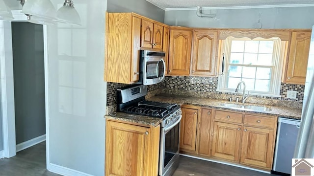 kitchen with sink, appliances with stainless steel finishes, ornamental molding, decorative backsplash, and dark stone counters