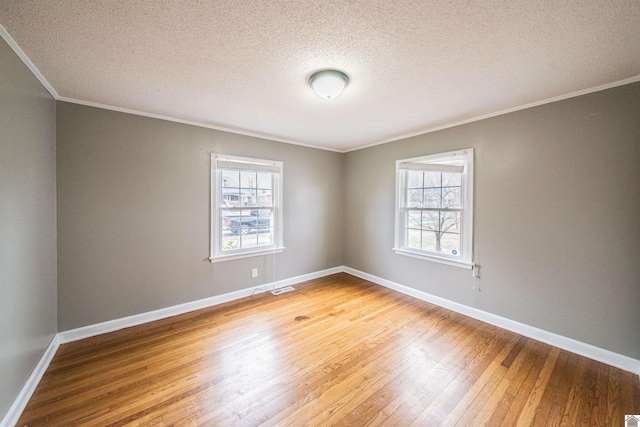 unfurnished room featuring ornamental molding, a healthy amount of sunlight, hardwood / wood-style floors, and a textured ceiling