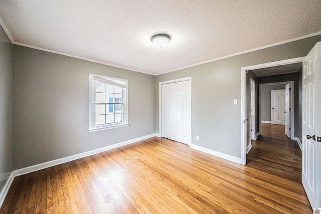 unfurnished bedroom featuring crown molding, wood-type flooring, a closet, and a textured ceiling