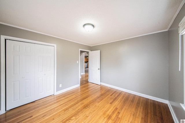 unfurnished bedroom featuring ornamental molding, light wood-type flooring, and a closet