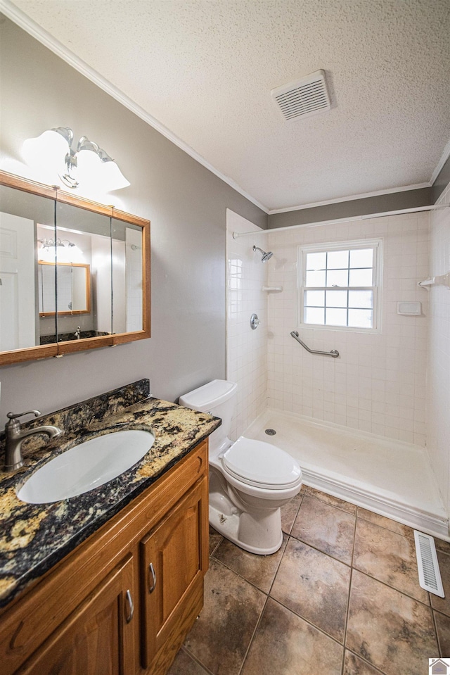 bathroom featuring tiled shower, vanity, ornamental molding, a textured ceiling, and toilet