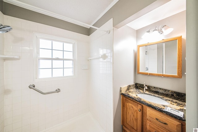 bathroom with vanity, ornamental molding, and a tile shower