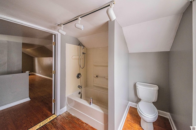 bathroom featuring lofted ceiling, hardwood / wood-style flooring, toilet, and washtub / shower combination