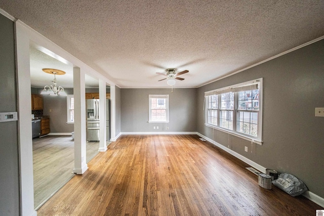 unfurnished living room with ceiling fan with notable chandelier, ornamental molding, a textured ceiling, and light wood-type flooring