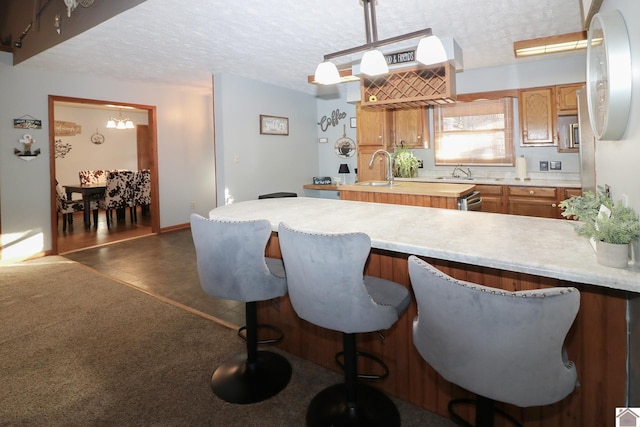 kitchen with sink, a textured ceiling, and decorative light fixtures