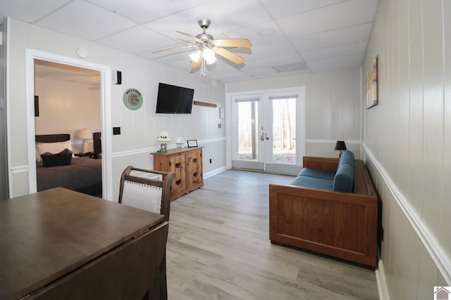 living room with a paneled ceiling, light hardwood / wood-style floors, french doors, and ceiling fan