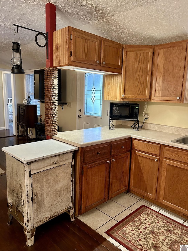 kitchen with pendant lighting, kitchen peninsula, a textured ceiling, and light tile patterned floors