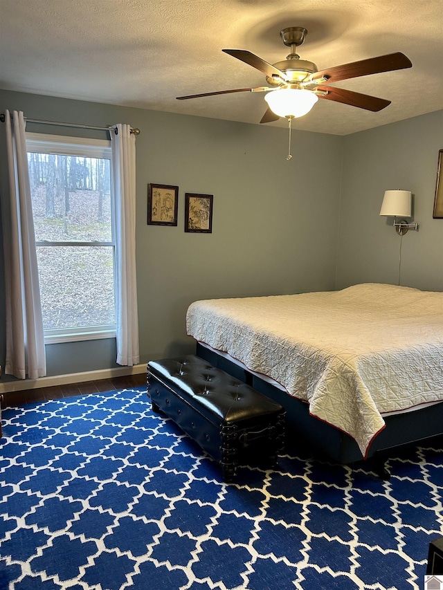 bedroom featuring ceiling fan, hardwood / wood-style floors, and a textured ceiling