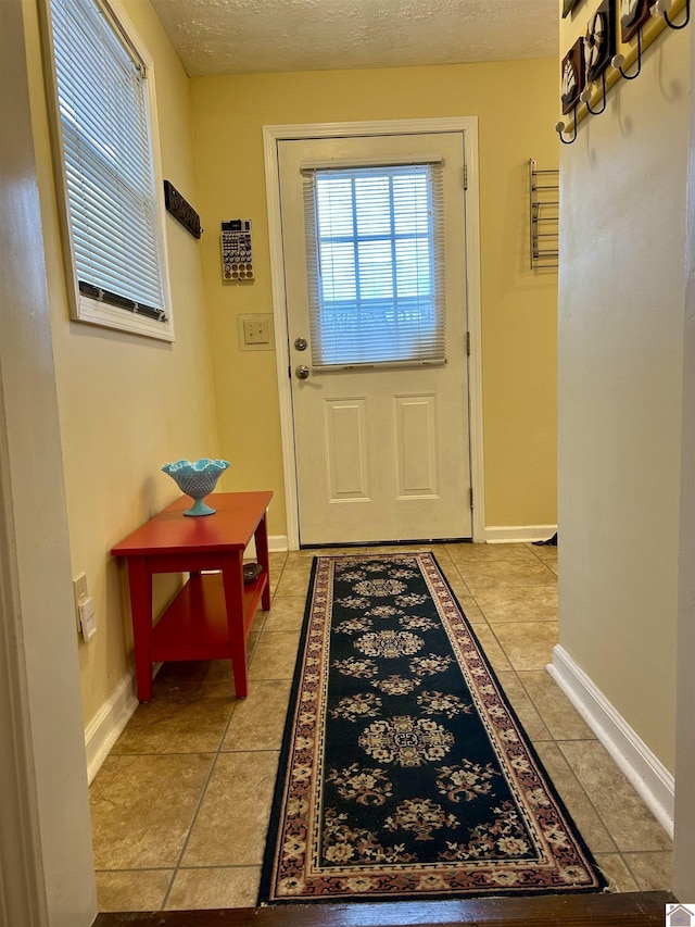 doorway to outside featuring a textured ceiling and light tile patterned floors