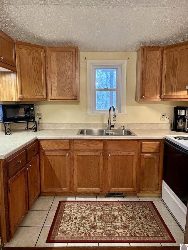 kitchen featuring light tile patterned floors, sink, a textured ceiling, and electric range