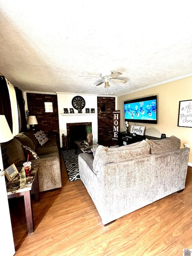 living room with hardwood / wood-style flooring, ornamental molding, a fireplace, and a textured ceiling