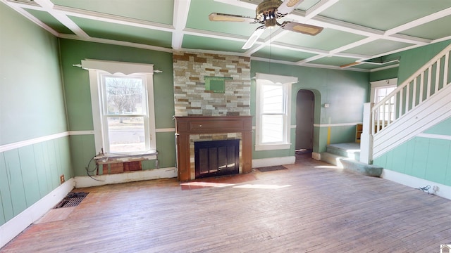 unfurnished living room featuring wood-type flooring, coffered ceiling, a large fireplace, and ceiling fan