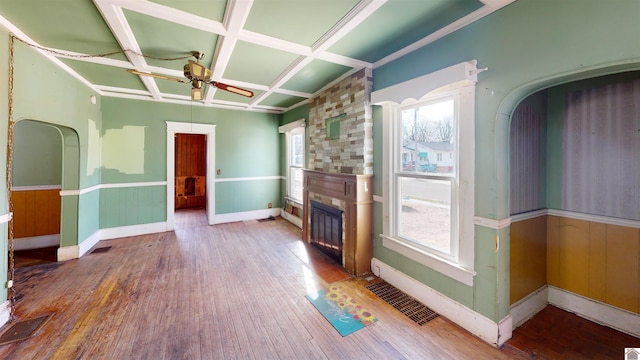 unfurnished living room with coffered ceiling, hardwood / wood-style floors, a large fireplace, and ceiling fan