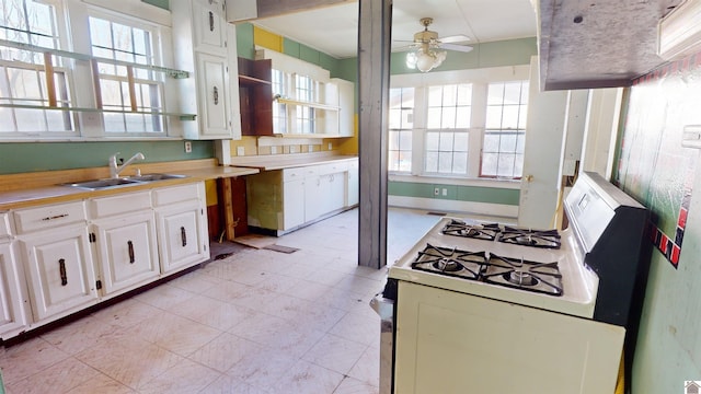 kitchen with white cabinetry, sink, white range with gas stovetop, and ceiling fan