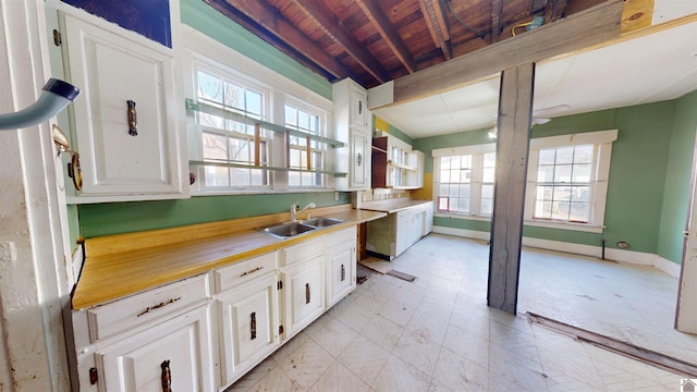 kitchen with beamed ceiling, sink, and white cabinets