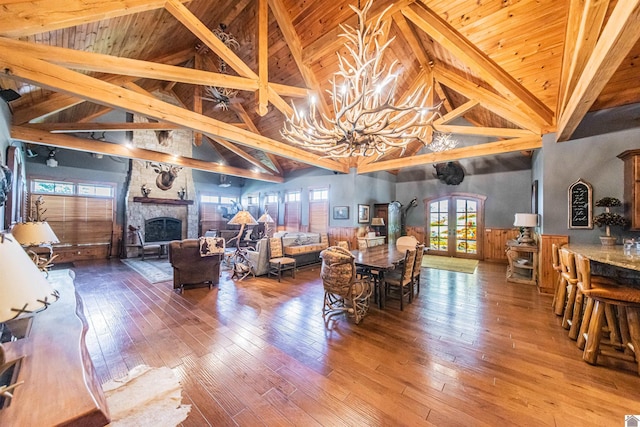 living room featuring beamed ceiling, a fireplace, french doors, and wood-type flooring