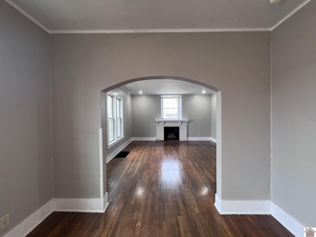 unfurnished living room with ornamental molding, a brick fireplace, and dark hardwood / wood-style flooring