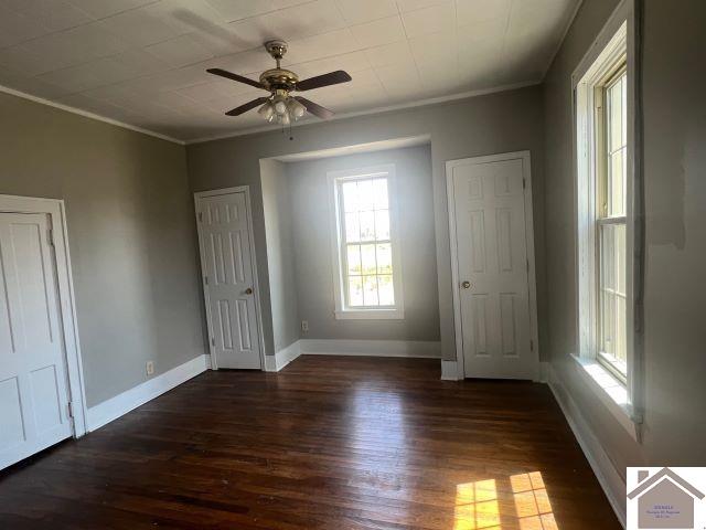 unfurnished bedroom with dark wood-type flooring and ornamental molding