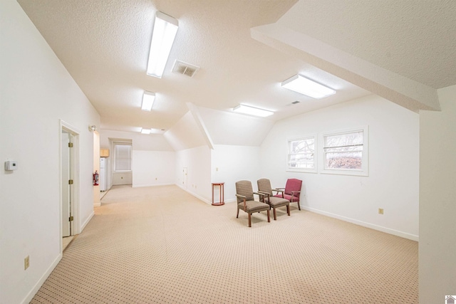 additional living space with lofted ceiling, light colored carpet, and a textured ceiling